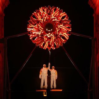 Olimpiadi, si accendono i bracieri in contemporanea. A Milano Tomba e Compagnoni, a Cortina Goggia