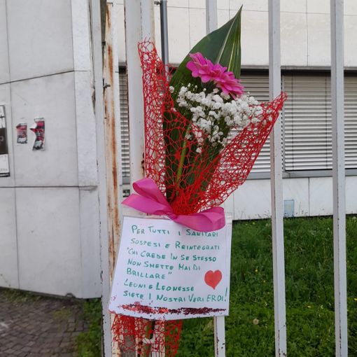 Magenta: &quot;No green pass&quot; depongono un mazzo di fiori sui cancelli del Fornaroli per omaggiare i sanitari prima sospesi e poi reintegrati