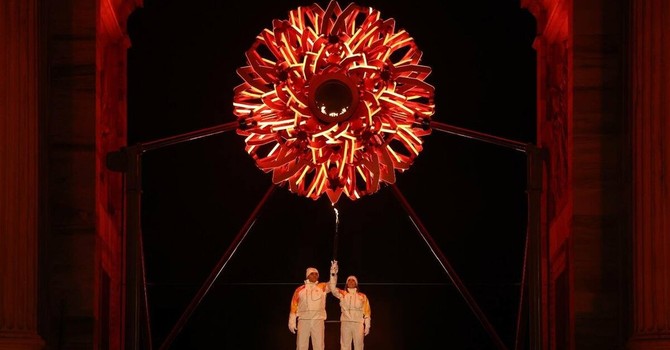 Olimpiadi, si accendono i bracieri in contemporanea. A Milano Tomba e Compagnoni, a Cortina Goggia